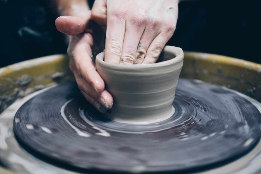Mans hands working clay pottery on pottery wheel