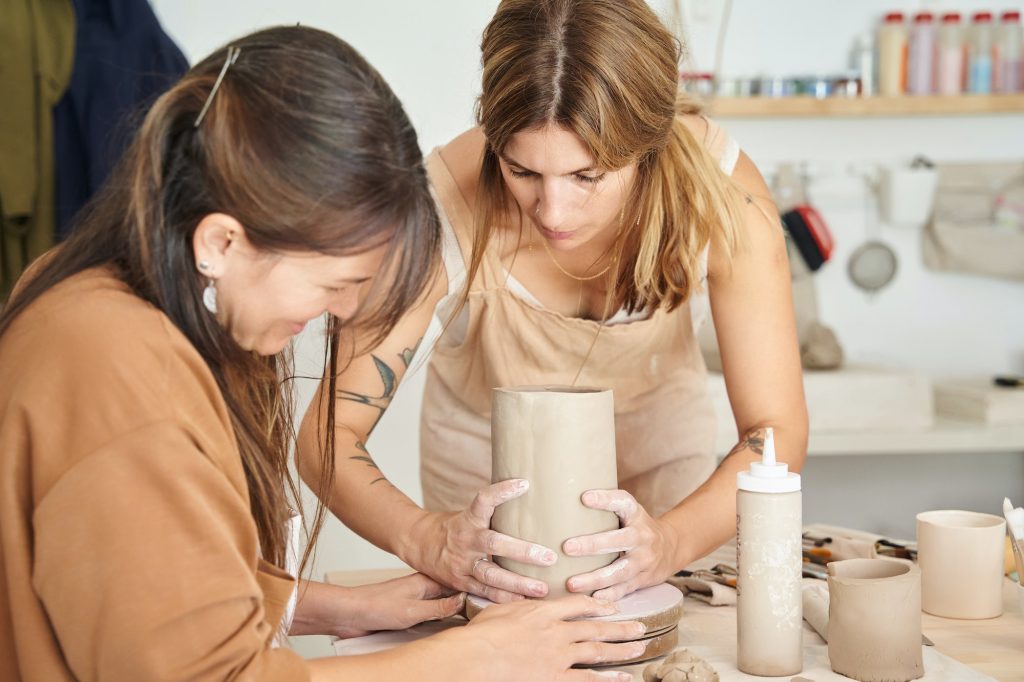 Two women working with clay in a pottery workshop.